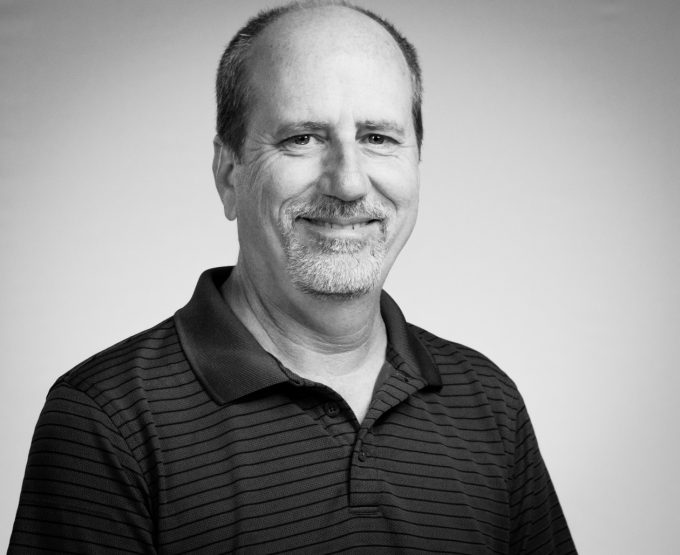 A black and white headshot of Mike Schuler